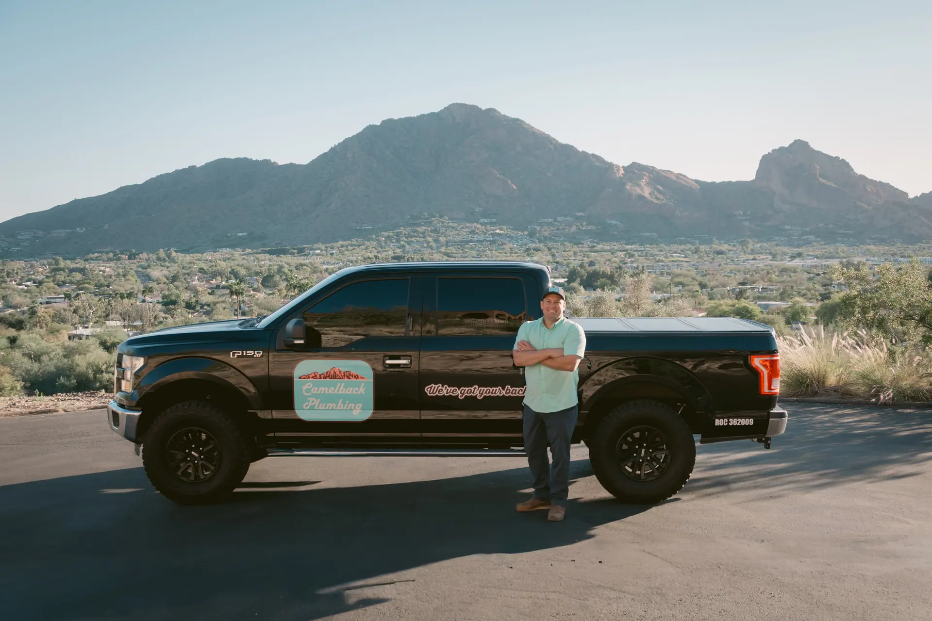 Gabe Sandersius beside the Camelback Plumbing service truck with Camelback Mountain behind him